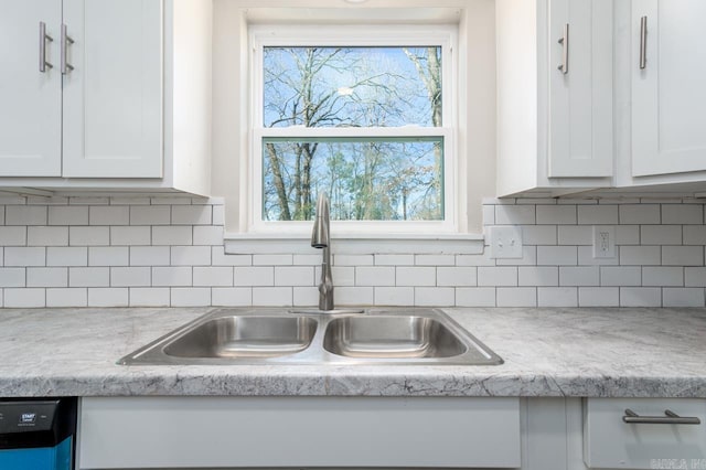 kitchen with light countertops, white cabinets, a sink, and dishwasher