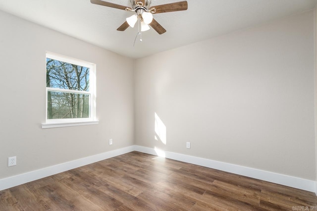 empty room with dark wood-style flooring, a ceiling fan, and baseboards