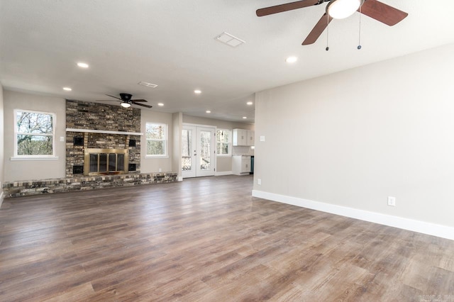 unfurnished living room with recessed lighting, a brick fireplace, a healthy amount of sunlight, and wood finished floors