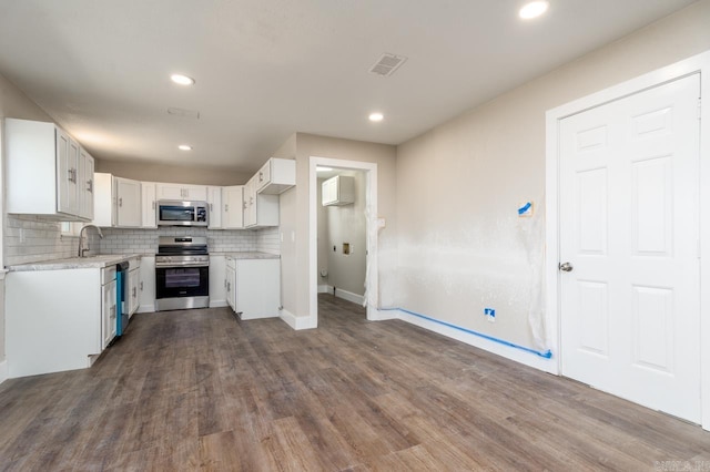 kitchen with light countertops, visible vents, backsplash, appliances with stainless steel finishes, and white cabinetry