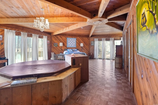 kitchen featuring a notable chandelier, plenty of natural light, wooden walls, and beam ceiling