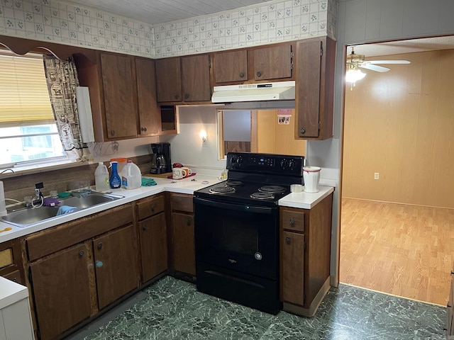 kitchen featuring light countertops, black electric range oven, a ceiling fan, a sink, and under cabinet range hood