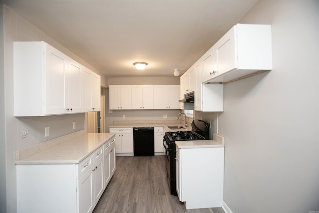 kitchen with white cabinets, under cabinet range hood, light countertops, black appliances, and a sink