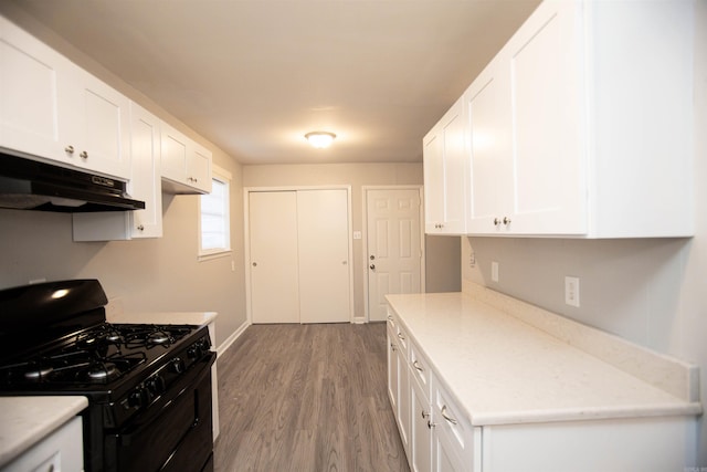 kitchen featuring light countertops, black gas range, white cabinetry, wood finished floors, and under cabinet range hood