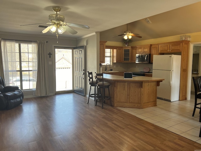 kitchen featuring a healthy amount of sunlight, stainless steel microwave, crown molding, and freestanding refrigerator