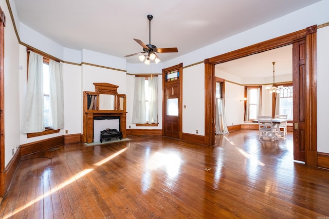 unfurnished living room featuring plenty of natural light, hardwood / wood-style floors, and ceiling fan with notable chandelier