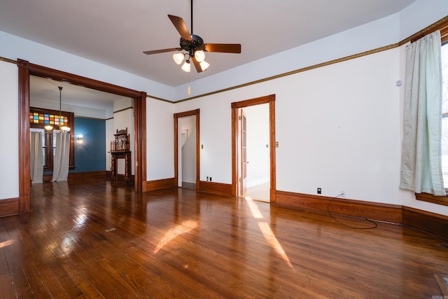 spare room featuring ceiling fan with notable chandelier, baseboards, and hardwood / wood-style flooring