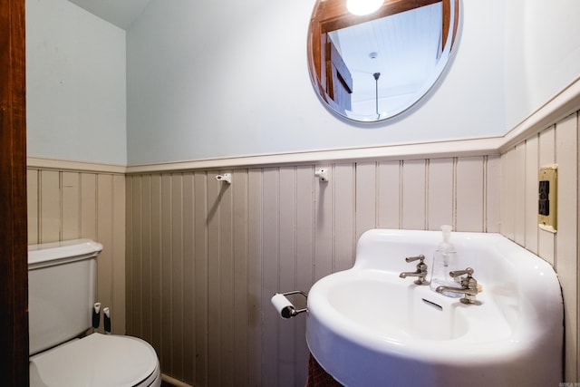 bathroom with a wainscoted wall, a sink, and toilet