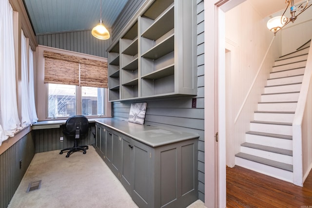 office area with wooden walls, lofted ceiling, built in study area, and visible vents