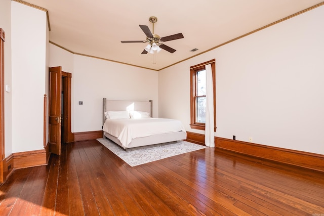 unfurnished bedroom with hardwood / wood-style flooring, a ceiling fan, baseboards, visible vents, and crown molding