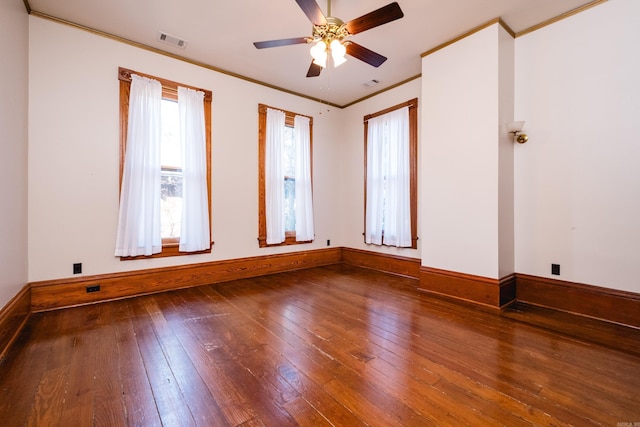 empty room with baseboards, crown molding, visible vents, and hardwood / wood-style floors