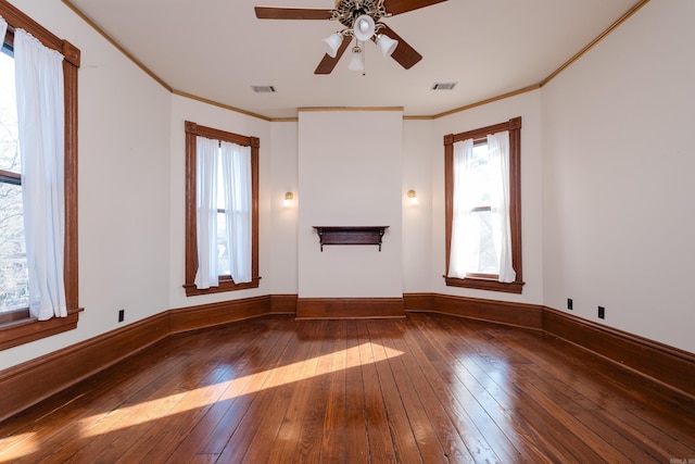 spare room with a healthy amount of sunlight, wood-type flooring, visible vents, and crown molding