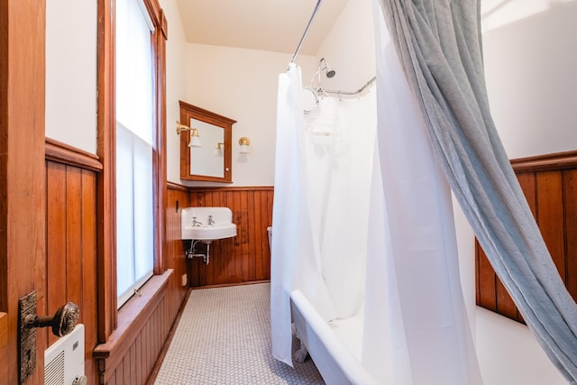 bathroom with a shower with curtain, a wainscoted wall, wooden walls, and tile patterned floors