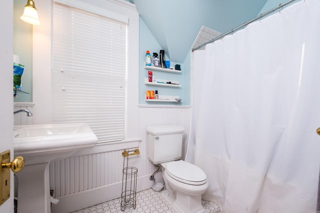 full bathroom with curtained shower, wainscoting, and toilet