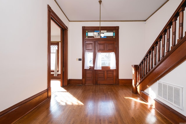 foyer with crown molding, visible vents, stairway, wood finished floors, and baseboards