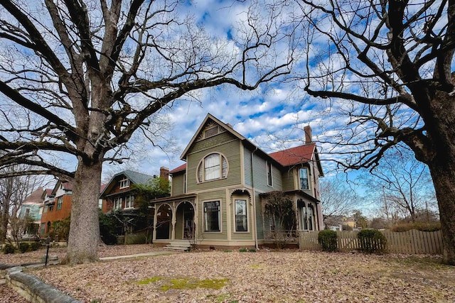 victorian house with a chimney and fence