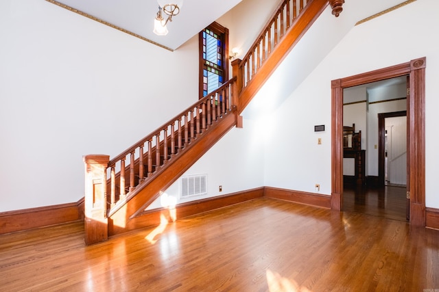 interior space featuring a towering ceiling, baseboards, visible vents, and wood finished floors