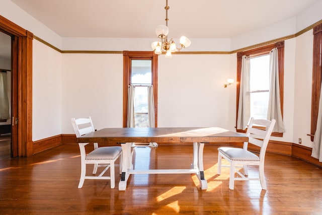 dining area featuring baseboards, wood finished floors, and an inviting chandelier