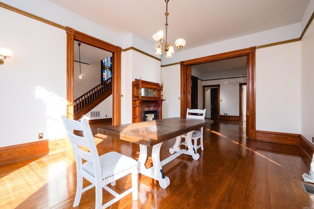 dining area with a chandelier, a fireplace, visible vents, stairway, and wood-type flooring