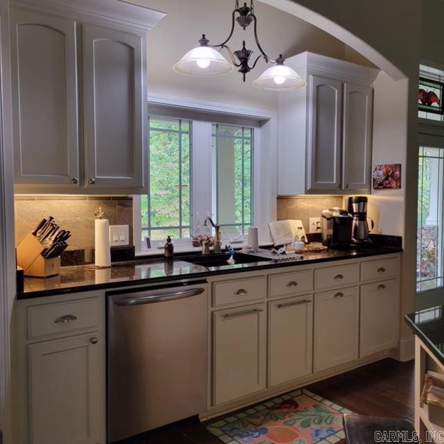 kitchen featuring a sink, dark wood-style floors, dishwasher, tasteful backsplash, and dark countertops