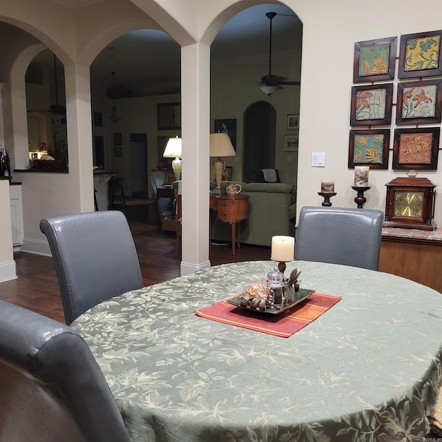 dining area featuring baseboards, a ceiling fan, arched walkways, and wood finished floors