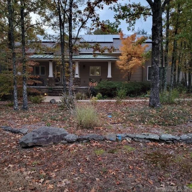 view of front facade with covered porch, solar panels, metal roof, and a standing seam roof