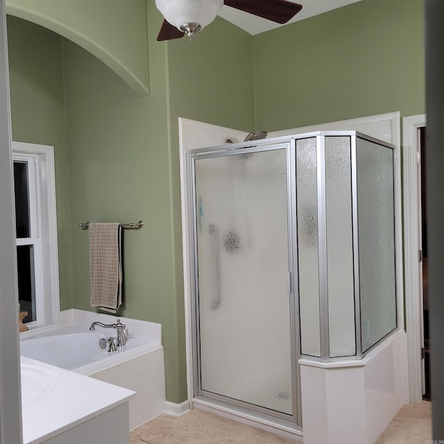 bathroom featuring a ceiling fan, a garden tub, and a shower stall