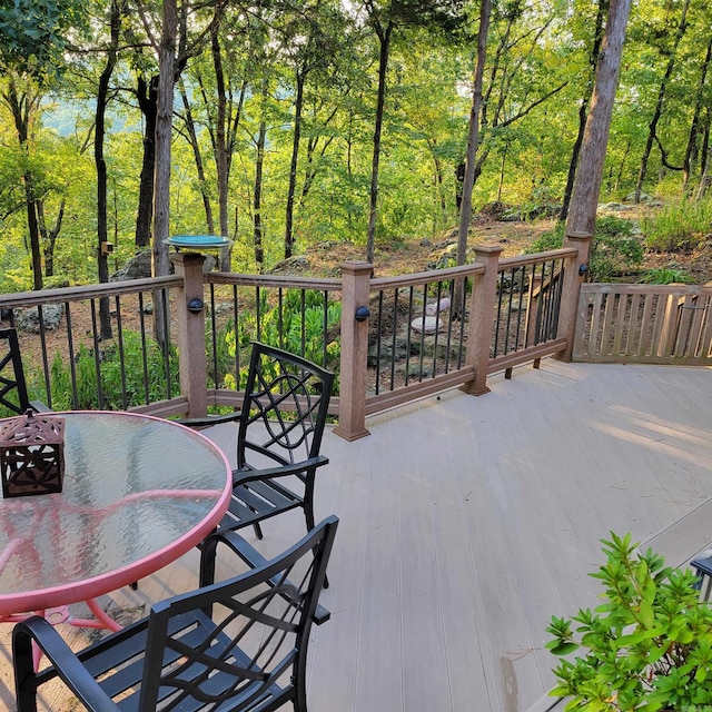 wooden deck featuring outdoor dining area and a view of trees