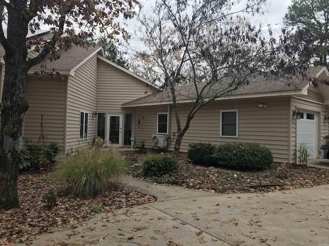 back of house with a garage and ac unit