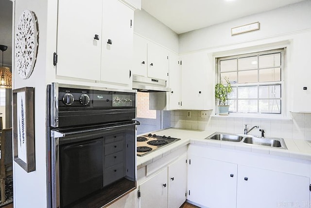 kitchen with decorative backsplash, a sink, oven, stovetop, and under cabinet range hood