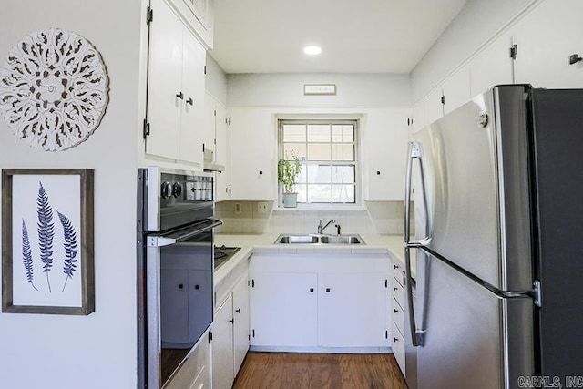 kitchen with wall oven, a sink, freestanding refrigerator, and white cabinetry