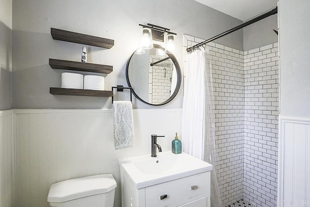 full bath with a stall shower, wainscoting, vanity, and toilet