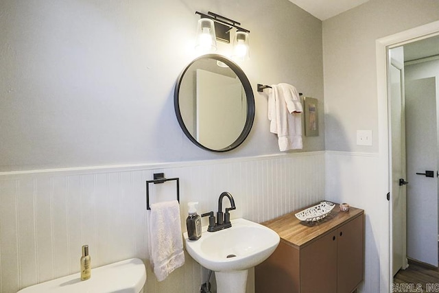 bathroom featuring a wainscoted wall, a sink, and toilet