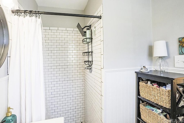 bathroom featuring a wainscoted wall and tiled shower