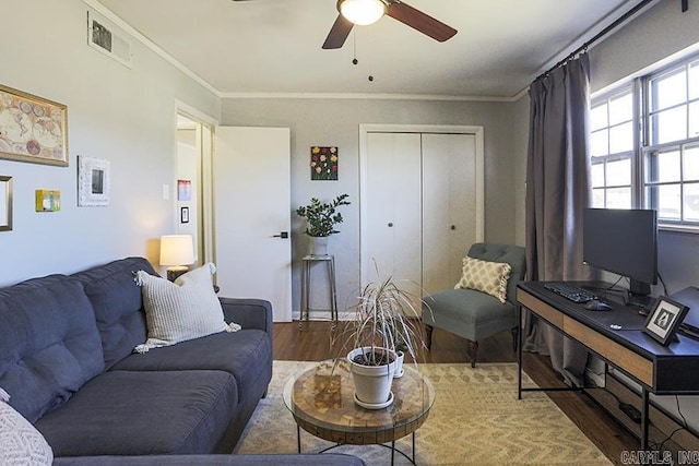 living area featuring ceiling fan, ornamental molding, wood finished floors, and visible vents