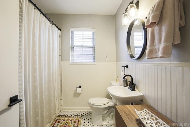 full bathroom with tile patterned flooring, a wainscoted wall, a sink, and toilet