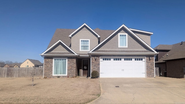 craftsman house with driveway, stone siding, and fence