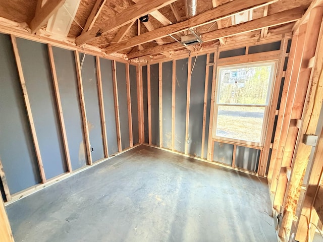 misc room with a garage and unfinished concrete floors