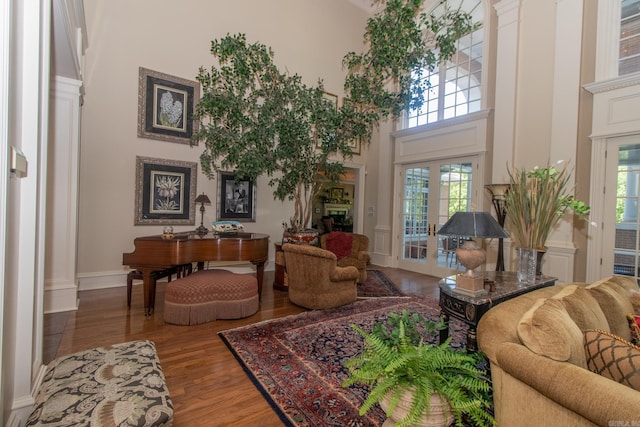 living area featuring french doors, wood finished floors, and a towering ceiling