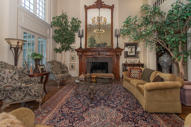 living area featuring a chandelier, a fireplace, a high ceiling, and wood finished floors