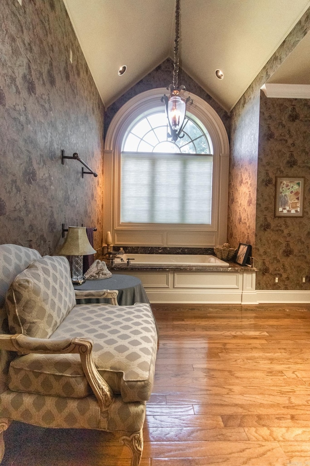 living area with lofted ceiling, wallpapered walls, and wood finished floors