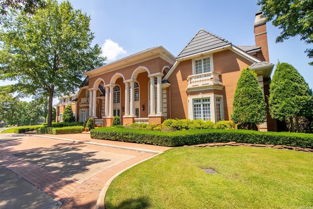 view of front of house with a front yard, brick siding, and a chimney