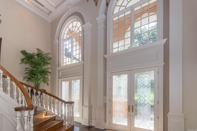 entryway with stairs, a high ceiling, ornamental molding, and french doors