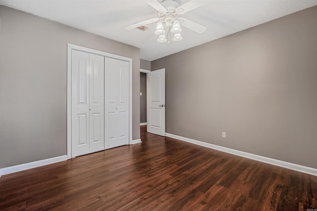 unfurnished bedroom featuring a ceiling fan, a closet, baseboards, and dark wood-style flooring