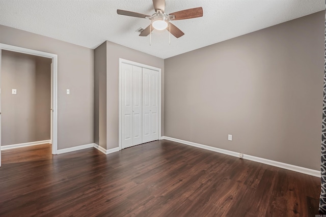 unfurnished bedroom featuring baseboards, a ceiling fan, dark wood-type flooring, a textured ceiling, and a closet