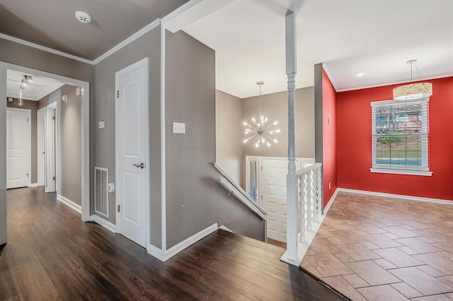 hallway featuring baseboards, visible vents, wood finished floors, crown molding, and a chandelier