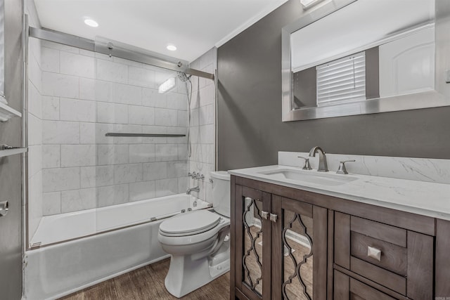 full bathroom with toilet, bath / shower combo with glass door, wood finished floors, and vanity