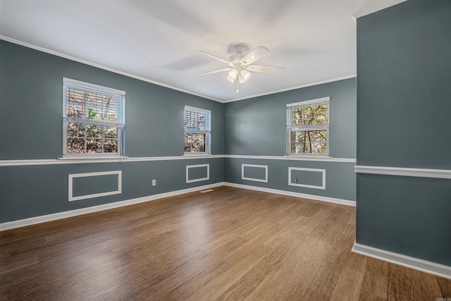 spare room with ornamental molding, plenty of natural light, baseboards, and wood finished floors