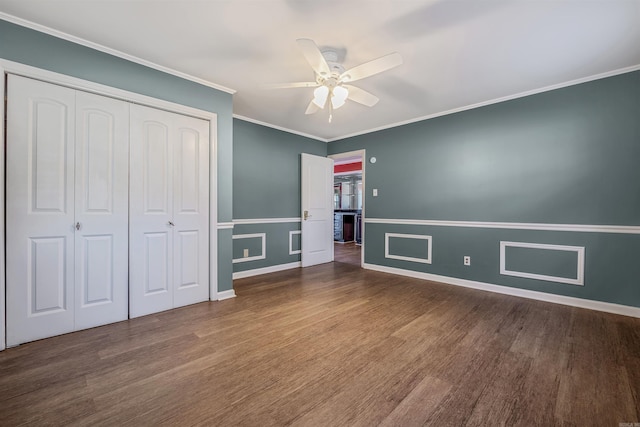 unfurnished bedroom featuring ornamental molding, a closet, wood finished floors, and baseboards