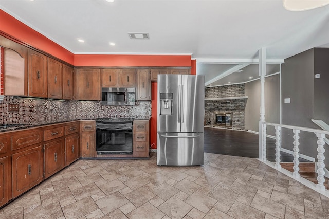 kitchen with tasteful backsplash, visible vents, appliances with stainless steel finishes, stone finish flooring, and a fireplace